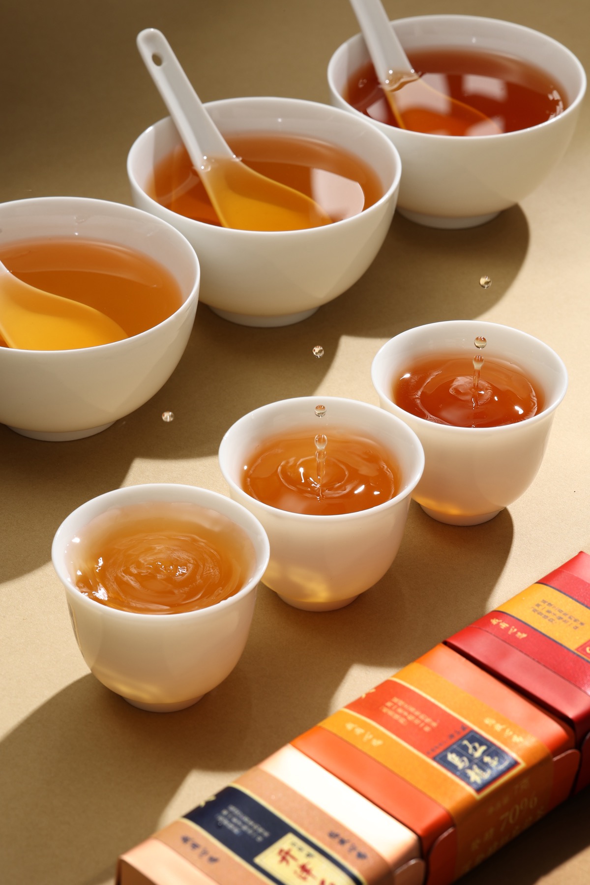 光下由金黄至橙红的多盏茶汤